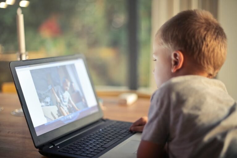 A young boy engrossed in watching content on a laptop in a cozy home setting.